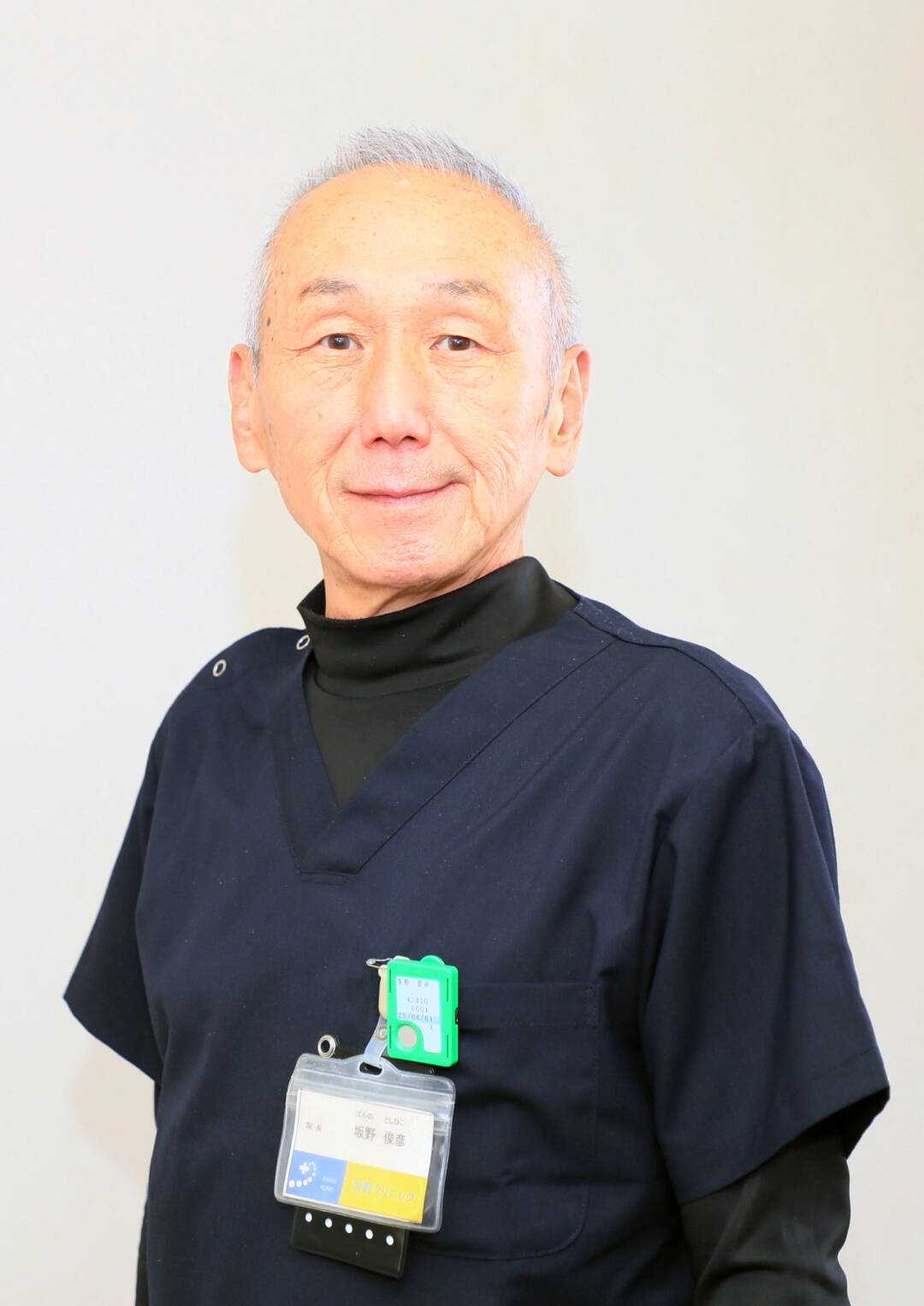 紺色の医療ユニフォームを着用した男性医師がカメラに向かって微笑んでいる